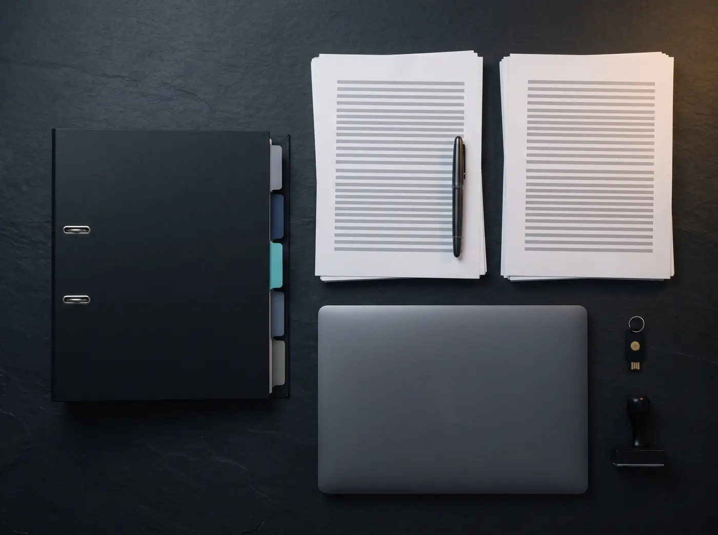 Mesa ordenada con archivador, documentos, portátil, llave de seguridad y sello